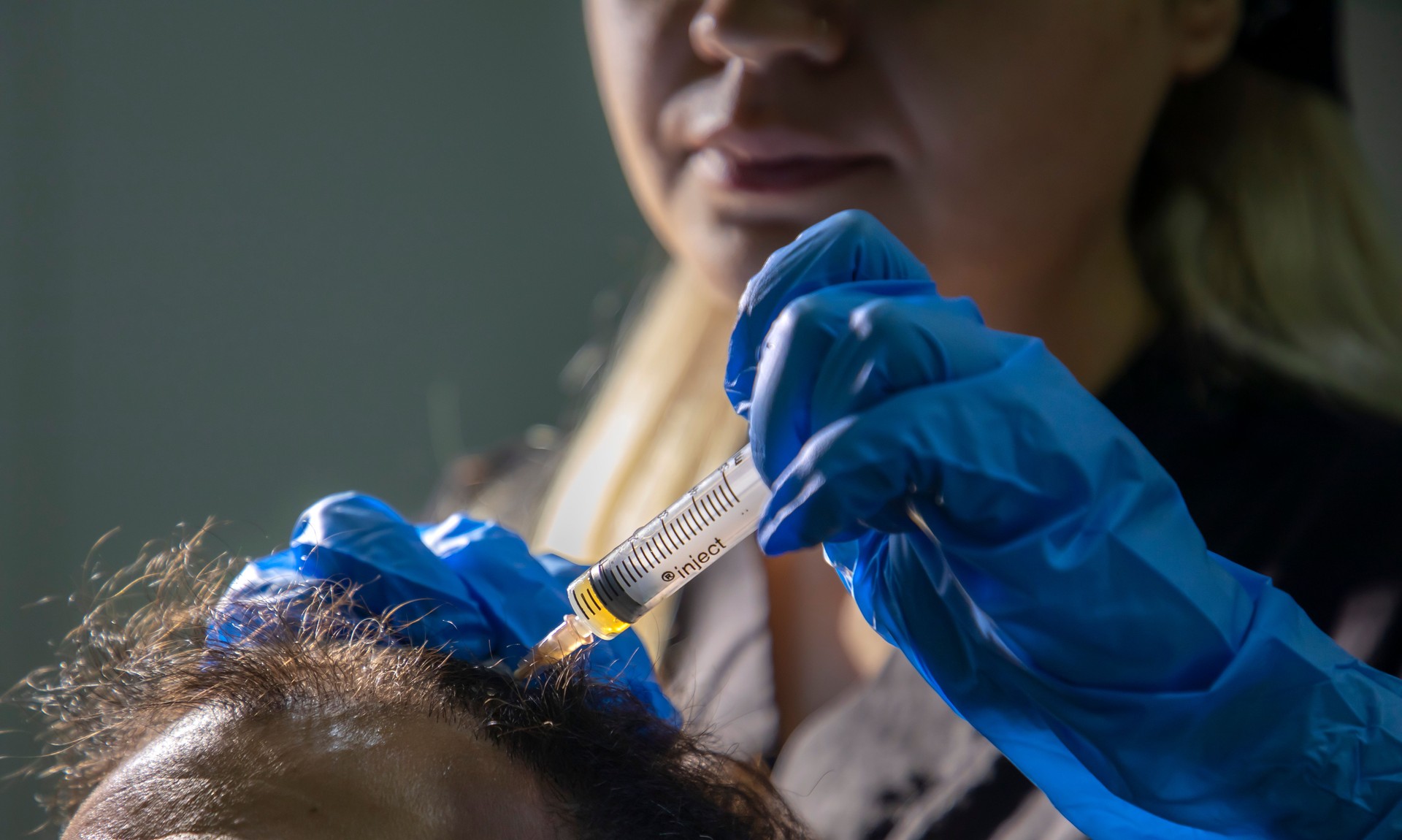 A young doctor performing prp on her male patient's hair