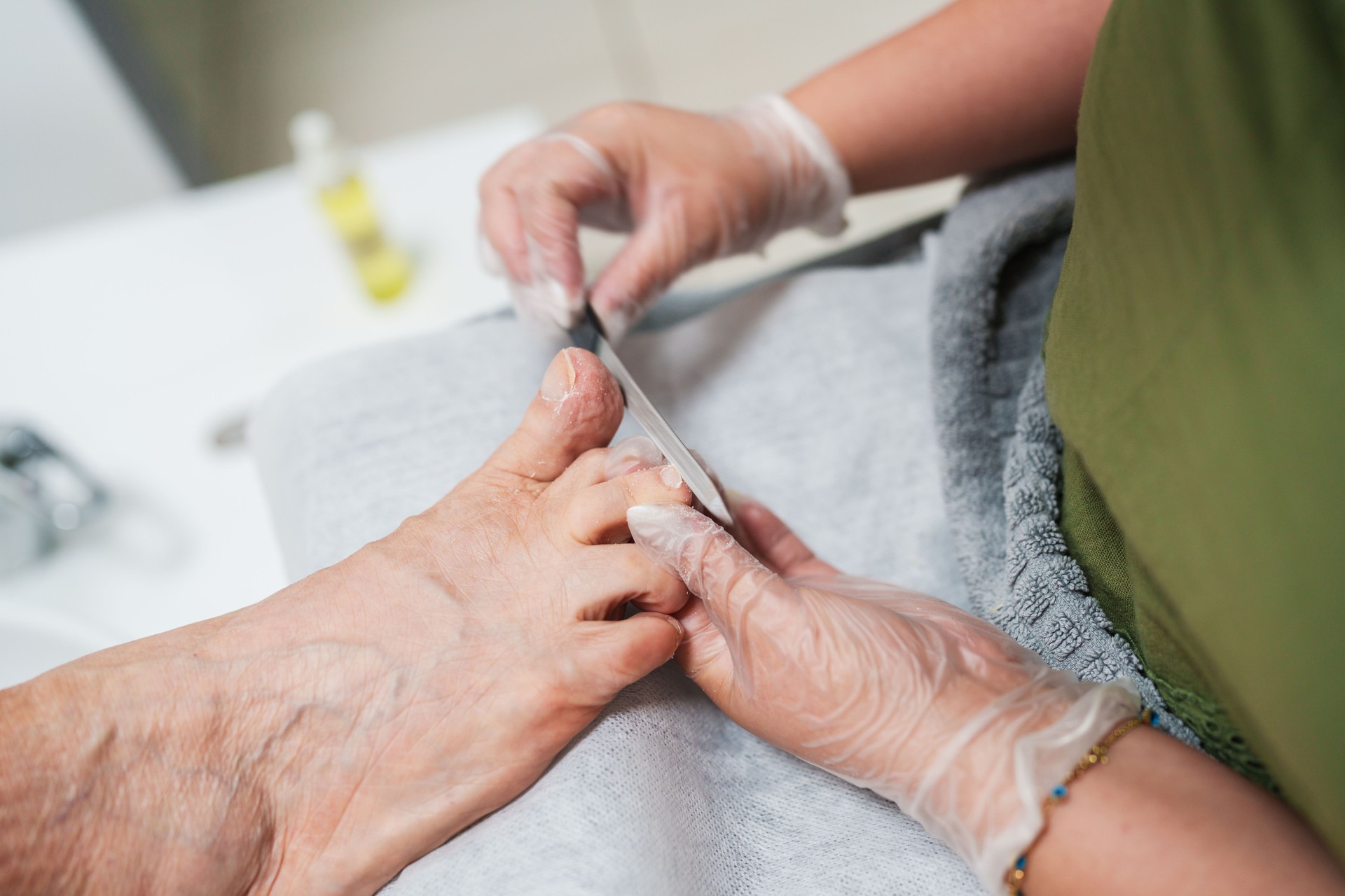 A beautician is filing an elderly woman's toenails.